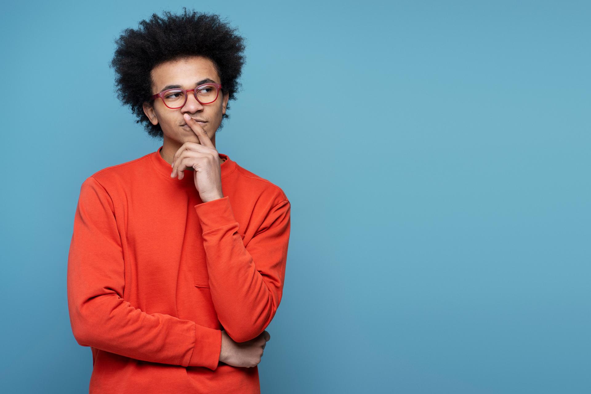 African American student wearing eyeglasses holding finger near face, looking for creative solution